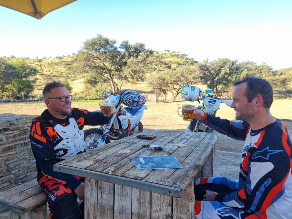 Two mountain bikers toasting with a beer after a ride at the trailhead