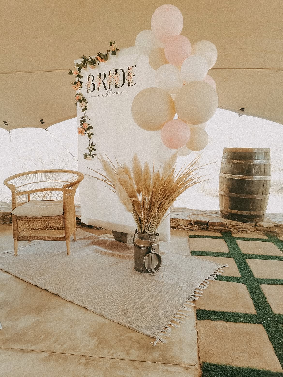 Bride in Bloom backdrop with balloon garland, rattan chair and pampas grass