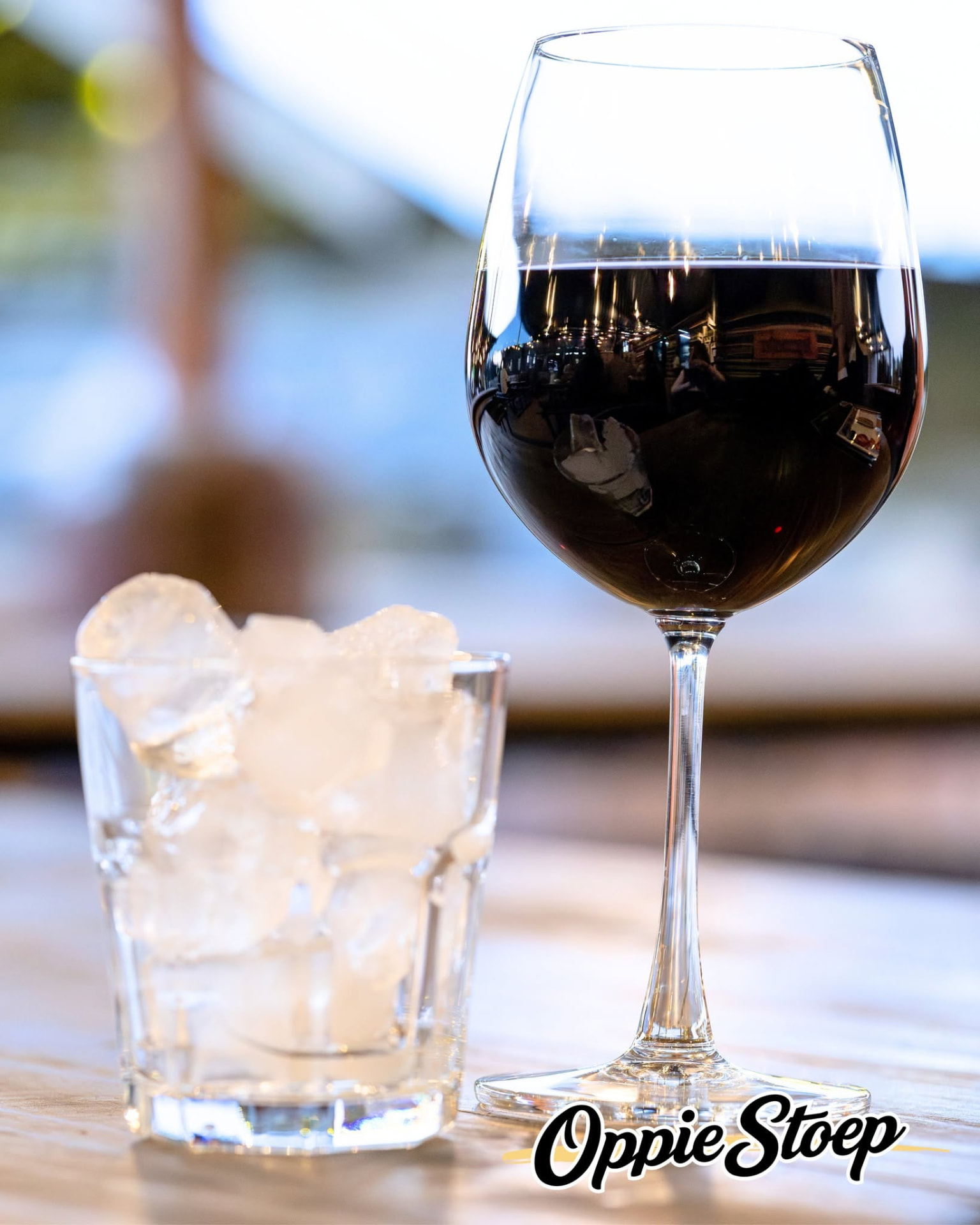 Glass of red wine and a glass of ice on a sunlit wooden table