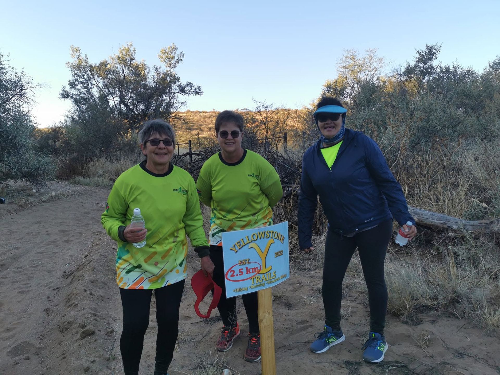 Three walkers at the Yellowstone Trails 2.5 km sign on a dirt track