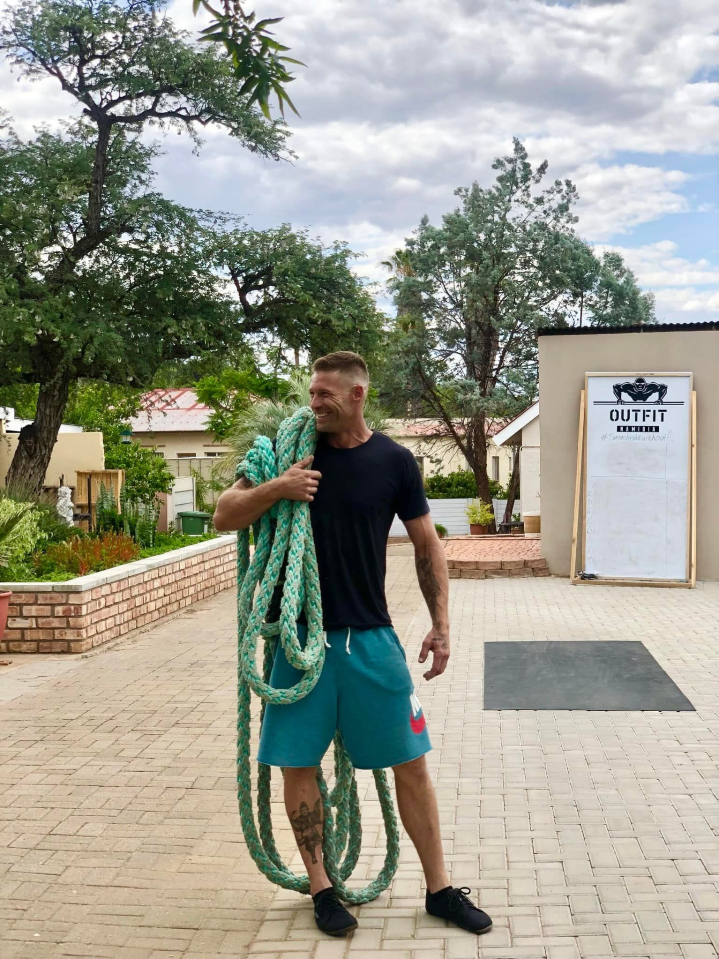 Coach shouldering a heavy rope at the Outfit Namibia training yard