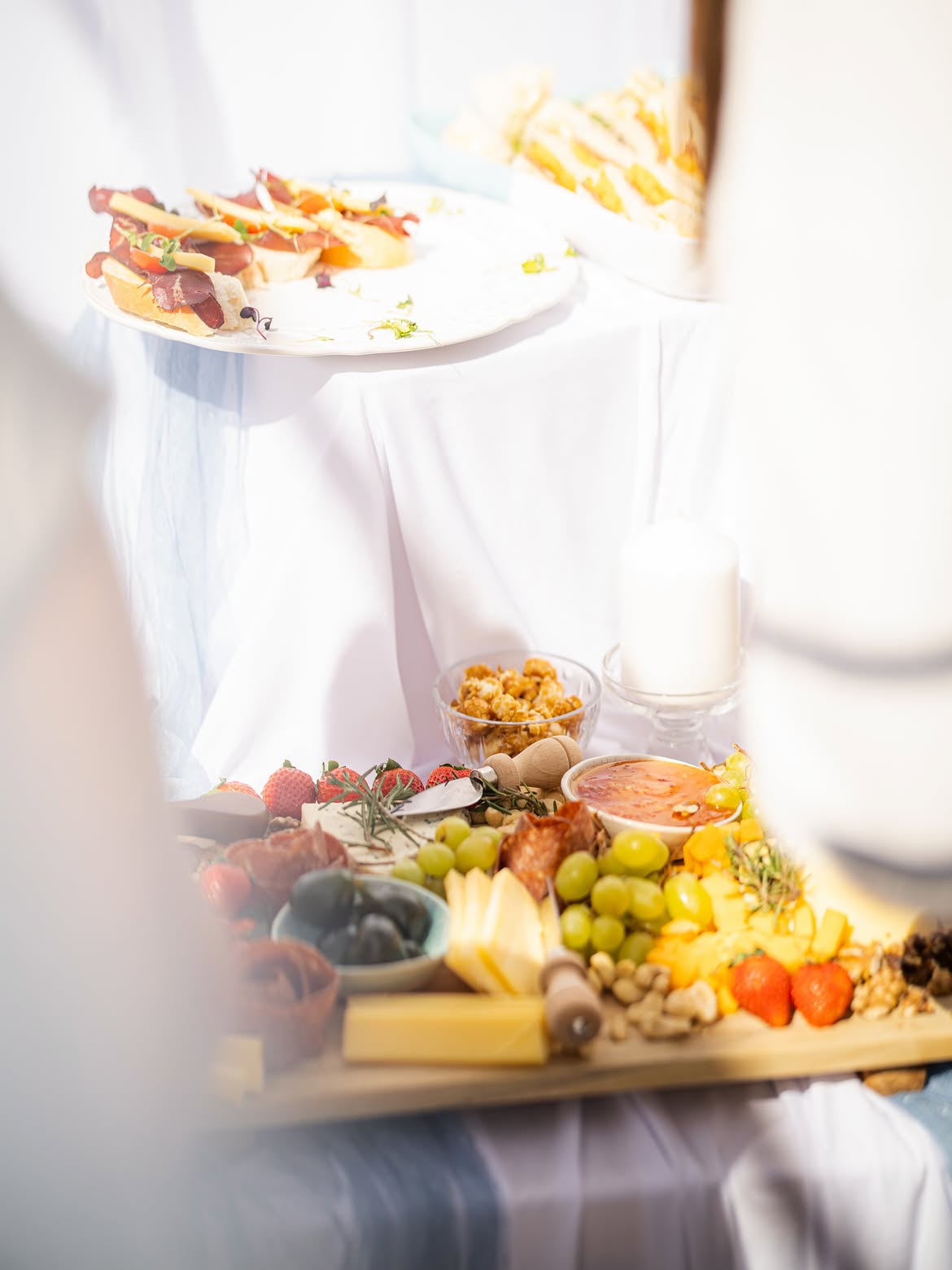 Platter of sesame meatball skewers beside a board of cured meat and cheese crostini