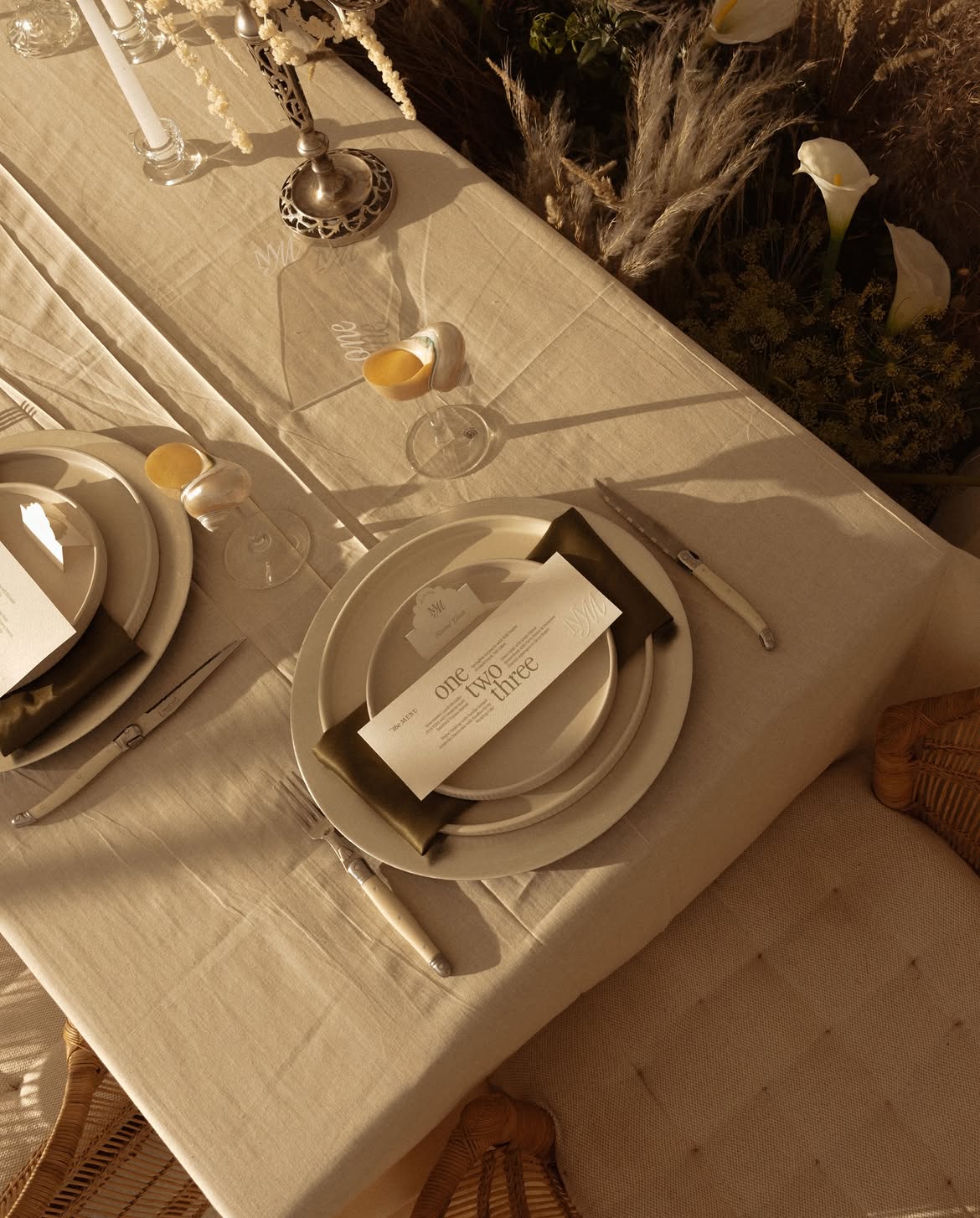 Place setting with menu card, olive napkin and pearl-stemmed glassware