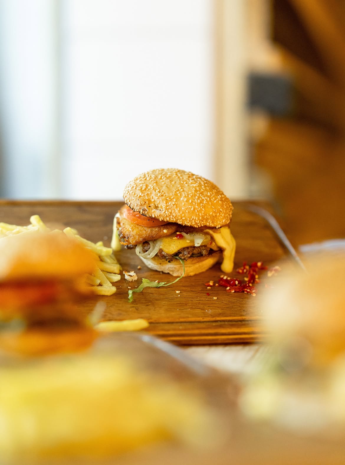 Sesame-bun burger with chips on a wooden table