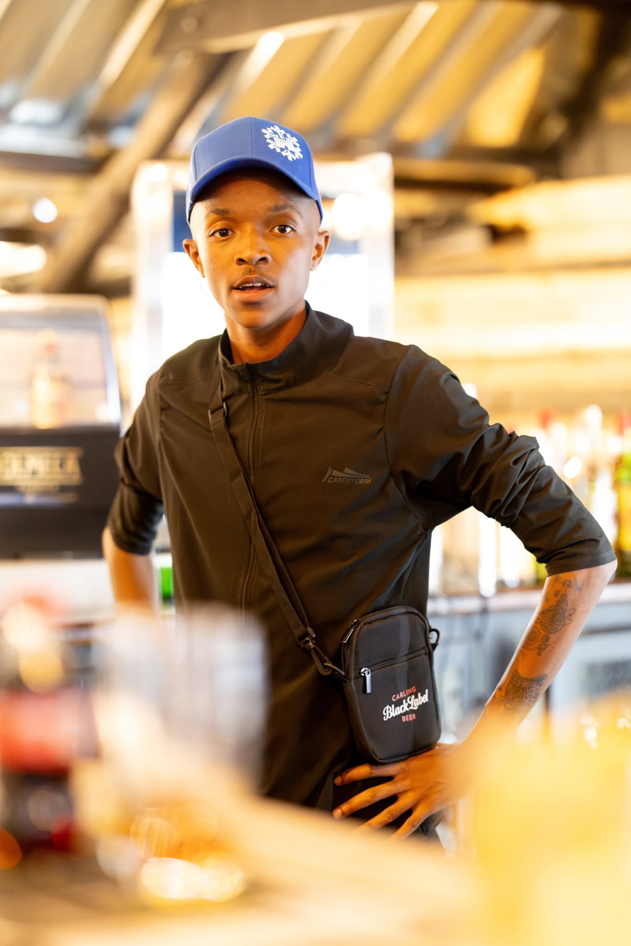 Barman in a blue cap standing behind the bar