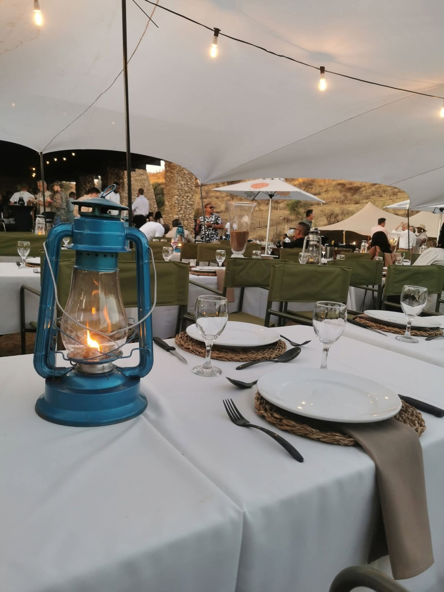 Blue paraffin lantern lit on a white-clothed table under the stretch tent