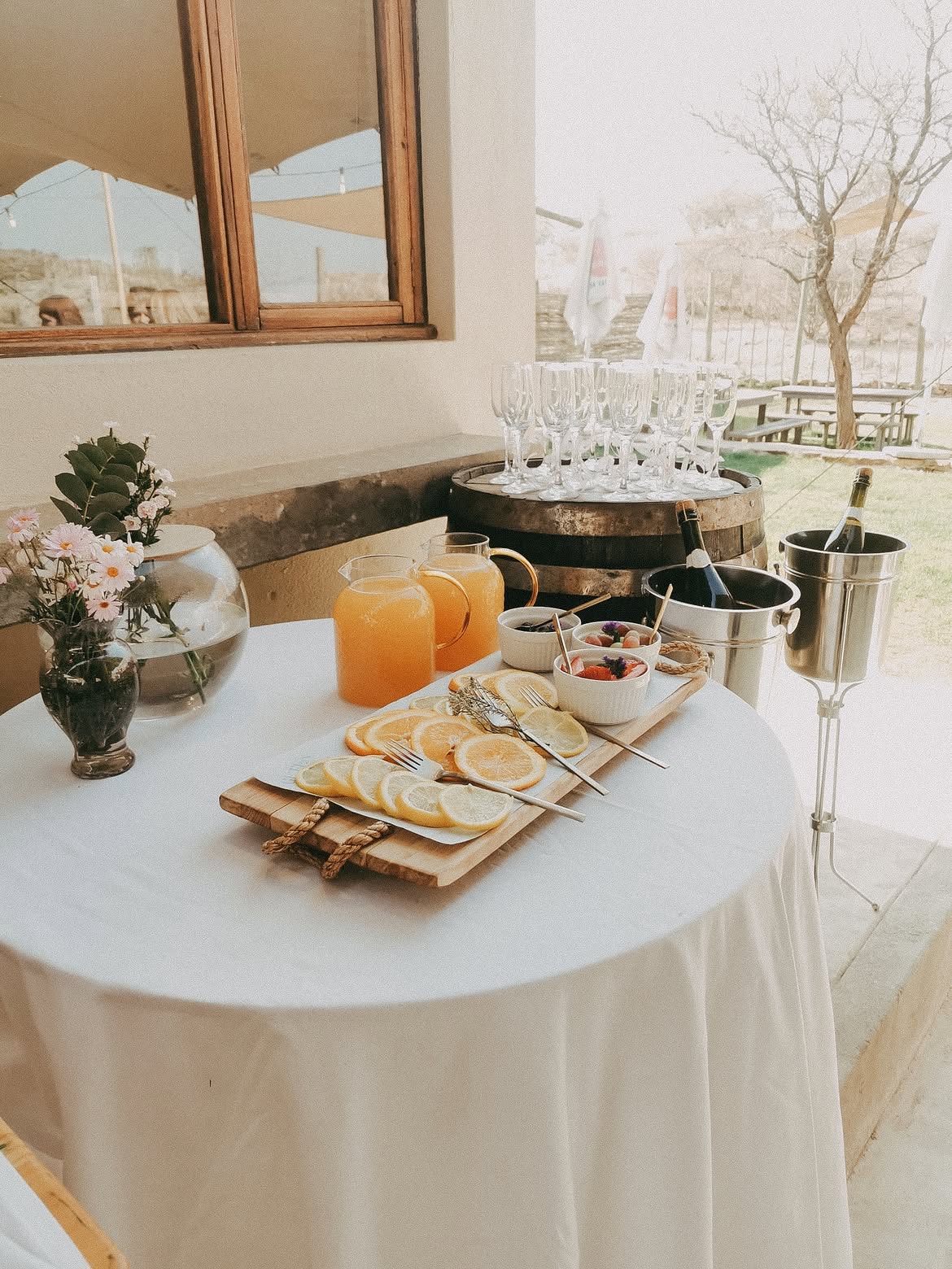 Welcome table with sparkling wine, juice jugs and a citrus platter on a wine barrel