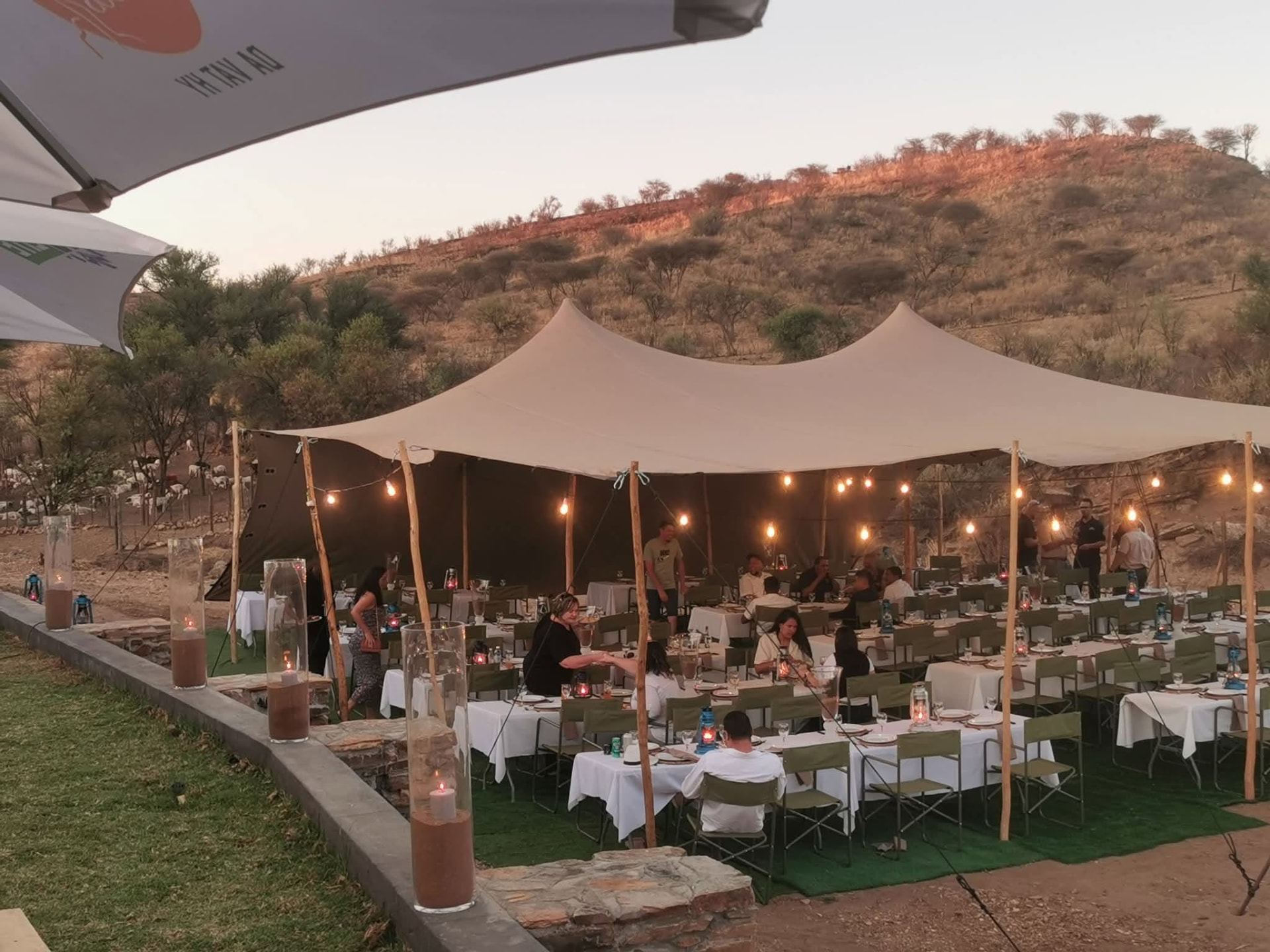 Guests dining under a stretch tent at Riverside Venue at dusk