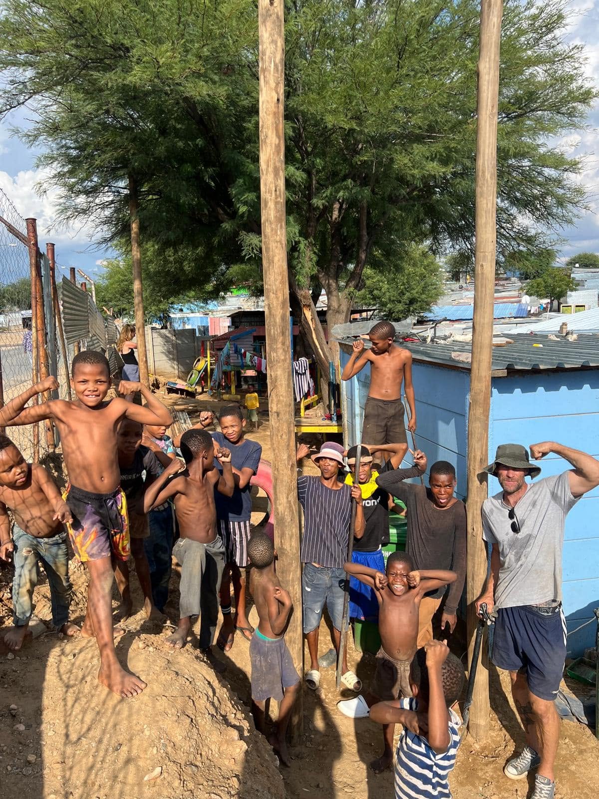 Outfit Namibia coach and neighbourhood kids raising poles on a community build day
