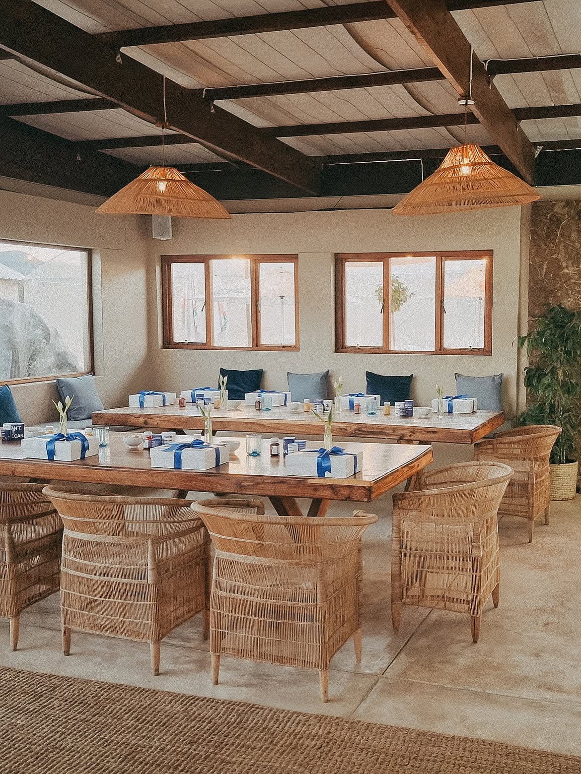 Long wooden tables set for a workshop with rattan chairs and woven pendant lights