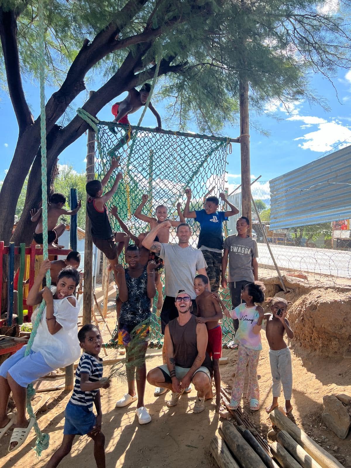 Coaches and children gathered around the finished community climbing net