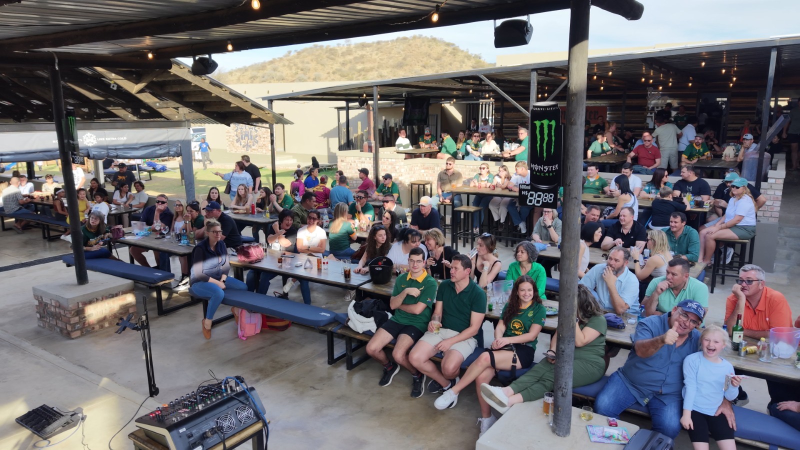 Crowd seated on the stoep watching the big screen at dusk