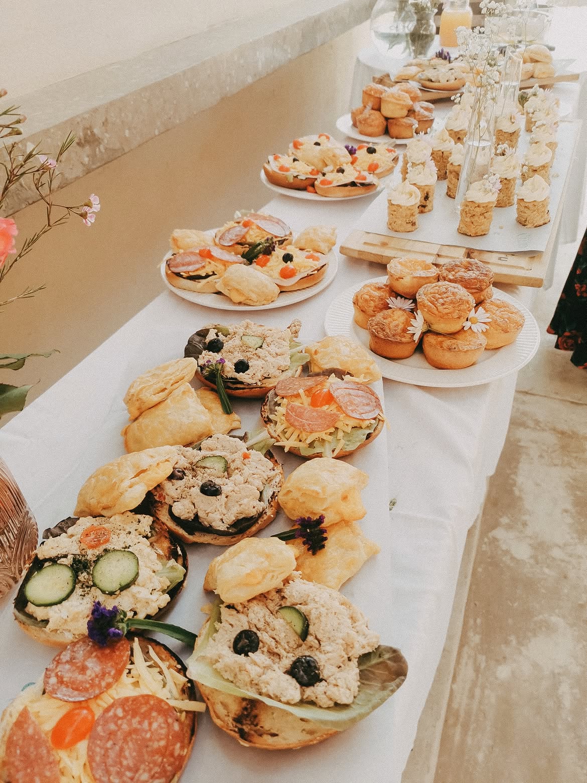 Grazing table of open sandwiches, quiches and cupcakes for a bridal shower