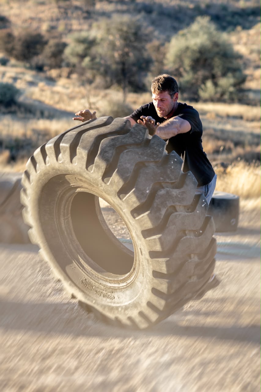 Coach flipping a heavy training tyre in the open veld at Outfit Namibia