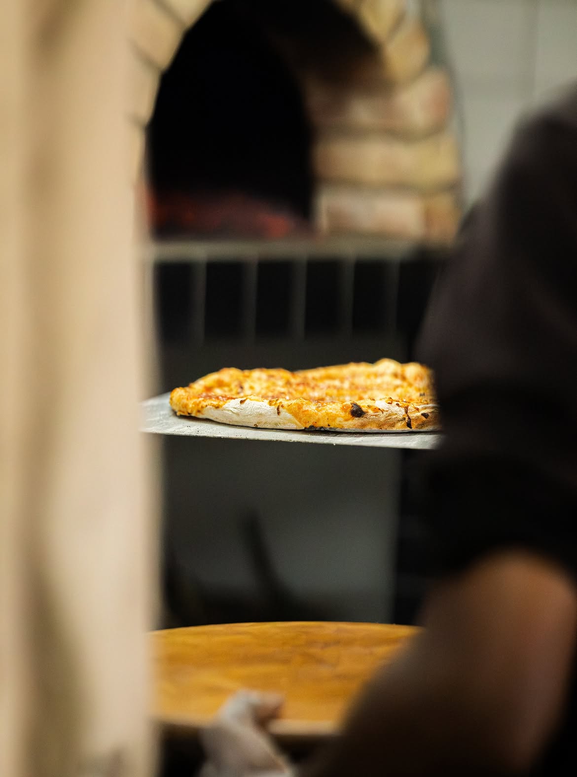 Baked wood-fired pizza carried out on a peel
